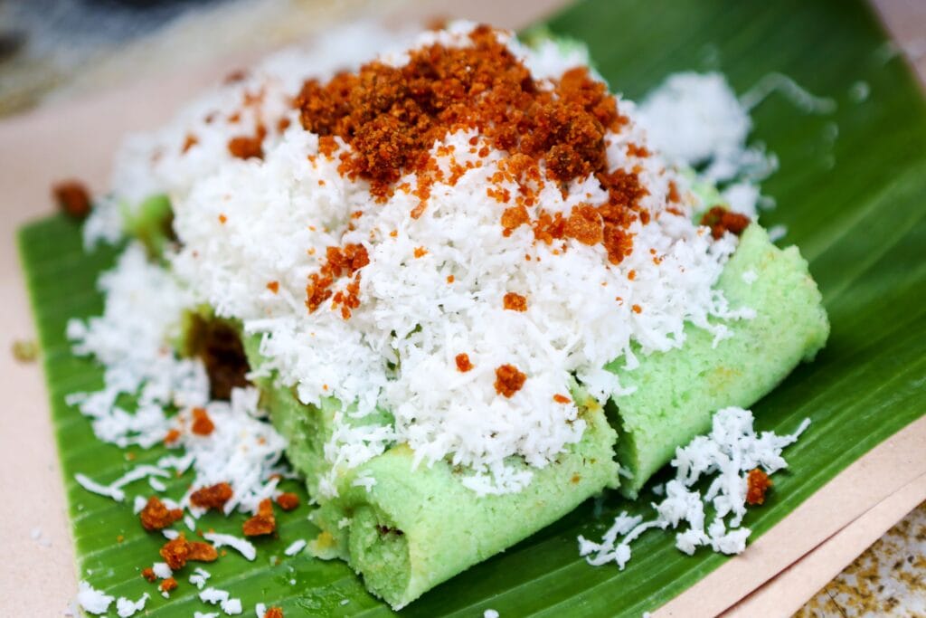 Close-up of Indonesian Putu Cake with coconut and sugar on a banana leaf.